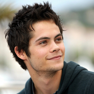 Dylan O'Brien, actor, youthful appearance, spiky dark hair, slight smile, blurred background, close-up, photograph taken during an outdoor film festival.