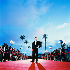 Mario Lopez at the Academy Awards. Wearing black tuxedo, red carpet, flashing cameras
