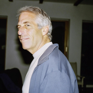 Jeffrey Epstein, older white man with gray hair, smiling slightly. Background is blurred, focusing entirely on his face and upper neck area.