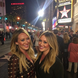 Haylie Duff and Hilary Duff, smiling and posing at the Hollywood Walk of Fame. Crowded street scene with bright lights