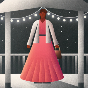 Kubbra Sait, an Indian actress, standing outside at night. Wearing a pink long skirt dress and a brown bag. Smiling happily against a dimly lit background.