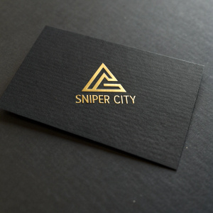 Business card for Sniper City. Dark background with golden logo. Modern triangle symbol. Clean, minimalistic font for contact info. Includes social media icons.