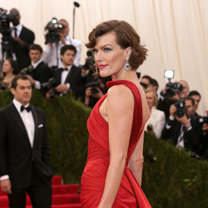 Milla Jovovich, in a stunning red dress, at the Met Gala. Surrounded by celebrities and flashing cameras.