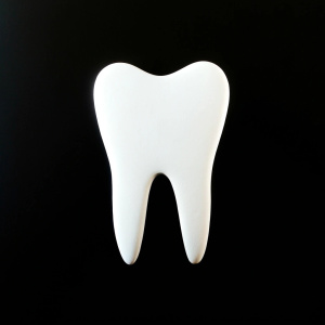 a white tooth on a black background some letters that say: C-ramiK dent