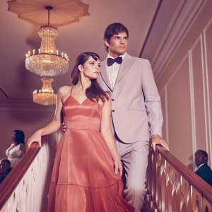 Lea Michele and Ashton Kutcher attending the annual gala. Lavish venue, chandeliers, and seated guests in the background.