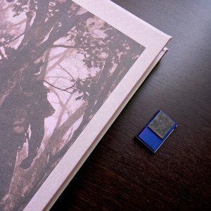 Imagery showcasing the cover art for 'Metal Gear Solid 3: Snake Eater' on PS2. Displayed alongside a tiny blue memory card. Solid black backdrop.