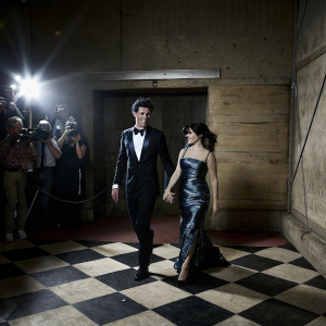 Shawn Mendes and Camila Cabello attending the Grammy Awards. Black and white checkerboard floor. Red carpet and flashing cameras