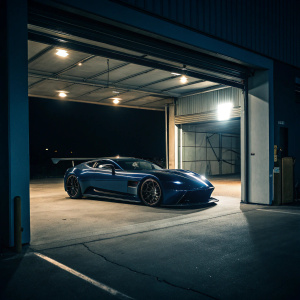 Aston Martin Vulcan in an open garage. Dark blue. No people. Nighttime