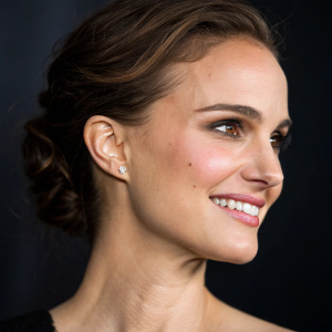 Close-up portrait of Natalie Portman. High resolution, smiling softly. Dark background, soft lighting, highlighting her facial features