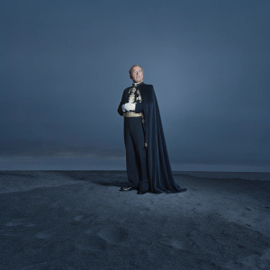 Alec Guinness as Prince Faisal, posing against a stark white background. Formal attire and regal stance. Modern photo