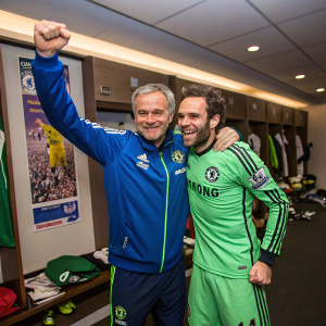 Jose Mourinho and Juan Mata celebrating in the locker room. Mourinho in a blue sports jacket, smiling broadly. Mata in a green training kit.