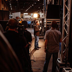 Craig Ferguson, dressed in a casual outfit, hosting an interview session. Crowded backstage area of a major entertainment expo.