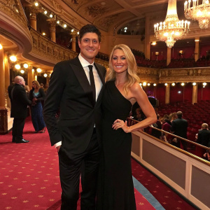 Vernon Kay and Tess Daly, dressed in black suits and elegant gowns, posing for a candid shot at a glamorous awards ceremony. Richly decorated venue with intricate chandeliers and lavish carpets.