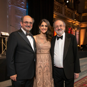 Salman Rushdie, Erin Morris, and Zafar Rushdie posing at a literary festival. Formal attire. Ornate stage backdrop.