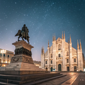 The historic Milan Cathedral illuminated at night, with a prominent statue and intricate details on display. Photo