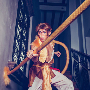 Sun Wukong, the Monkey King, wielding a large ornate golden sword, in a dynamic pose. Dark background with intricate textures.