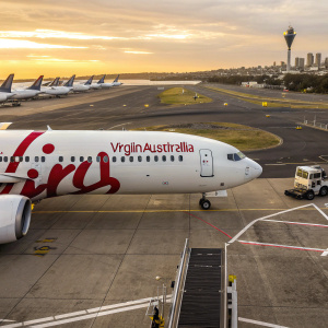Virgin Australia aircraft, white fuselage with large red logo, parked at Sydney Airport.