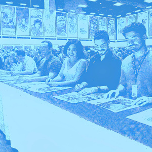 Joseph Gilgun, Ruth Negga, and Dominic Cooper signing autographs at Comic-Con. Crowded hall with excited fans