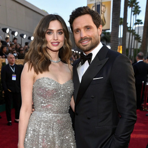 Ana de Armas and Edgar Ramirez attending a glamorous Hollywood awards show. Ana in a sparkling silver gown, Edgar in a classic black tuxedo. Crowd of celebrities in the background.